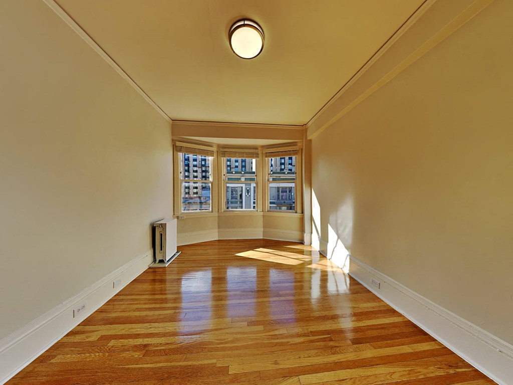 a empty living room with wood floors and windows