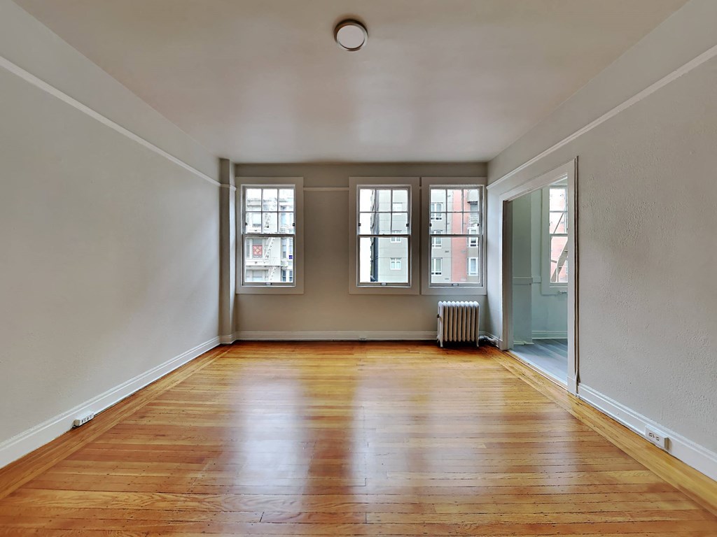 an empty living room with wood floors and windows