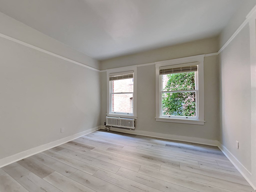 a living room with wood floors and two windows