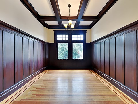A long hallway with wooden floors and dark wood paneling on the walls.