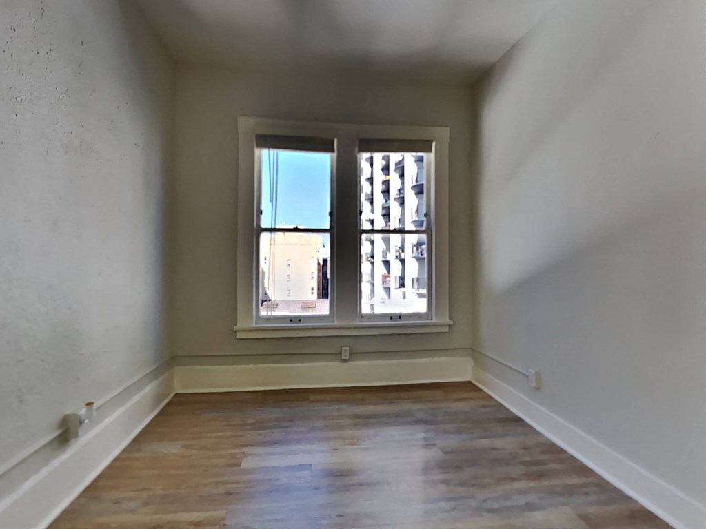 a empty room with a window and wooden floors