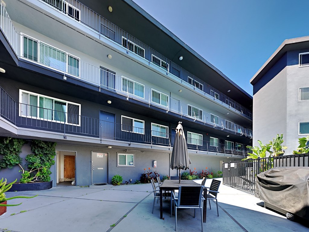 a patio with a table and chairs in front of an apartment building