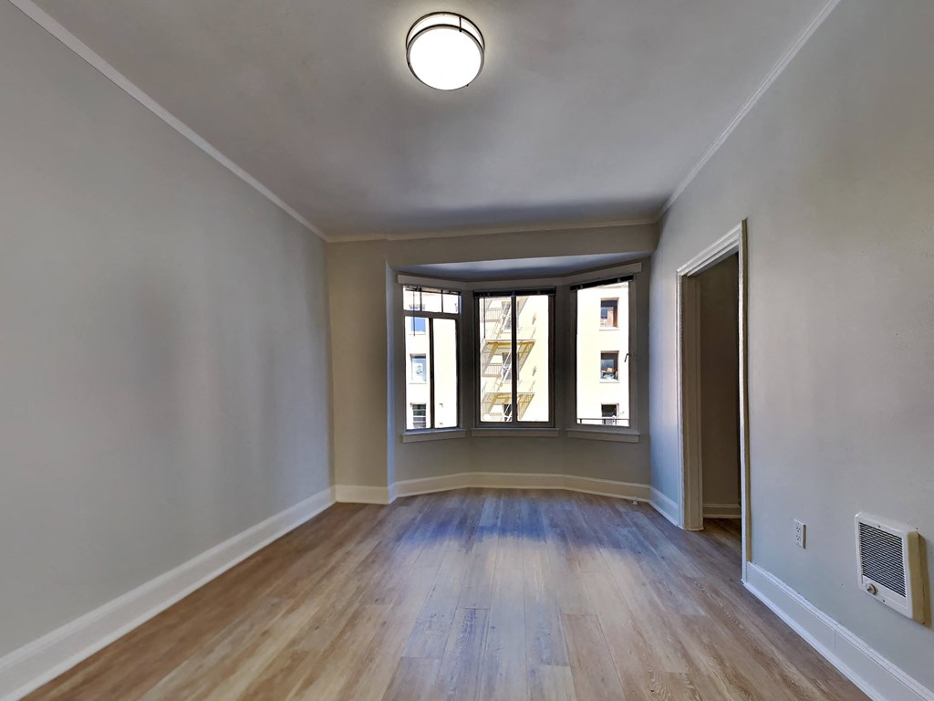 an empty living room with a large window and wooden floors