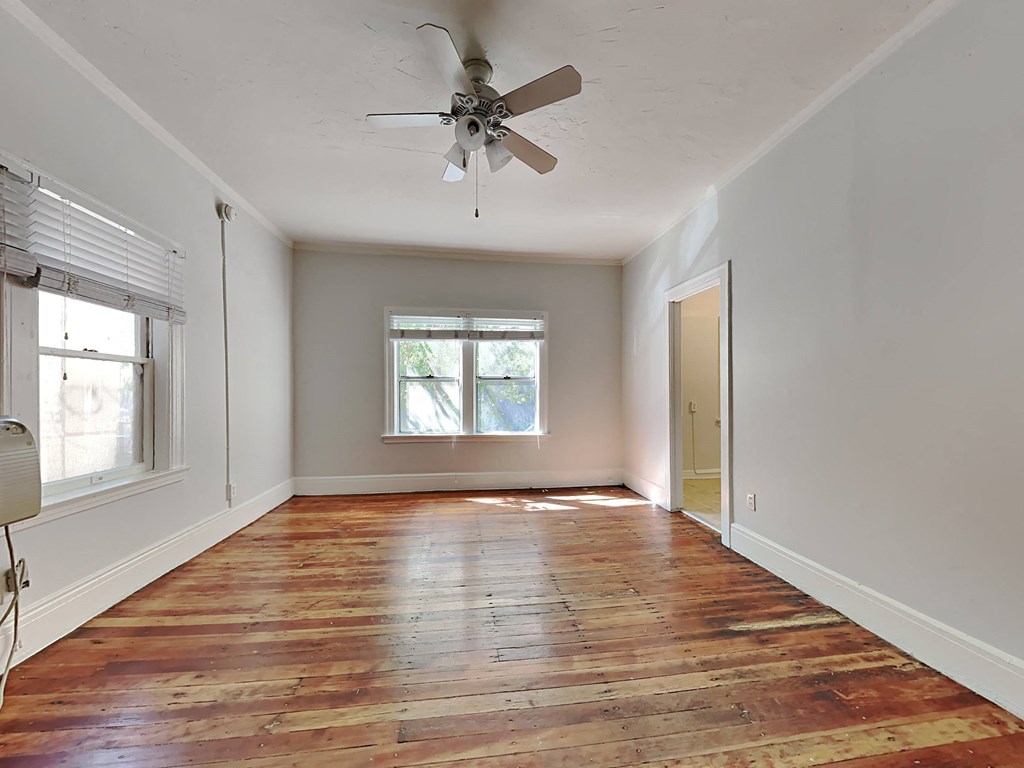 an empty living room with a ceiling fan and a window