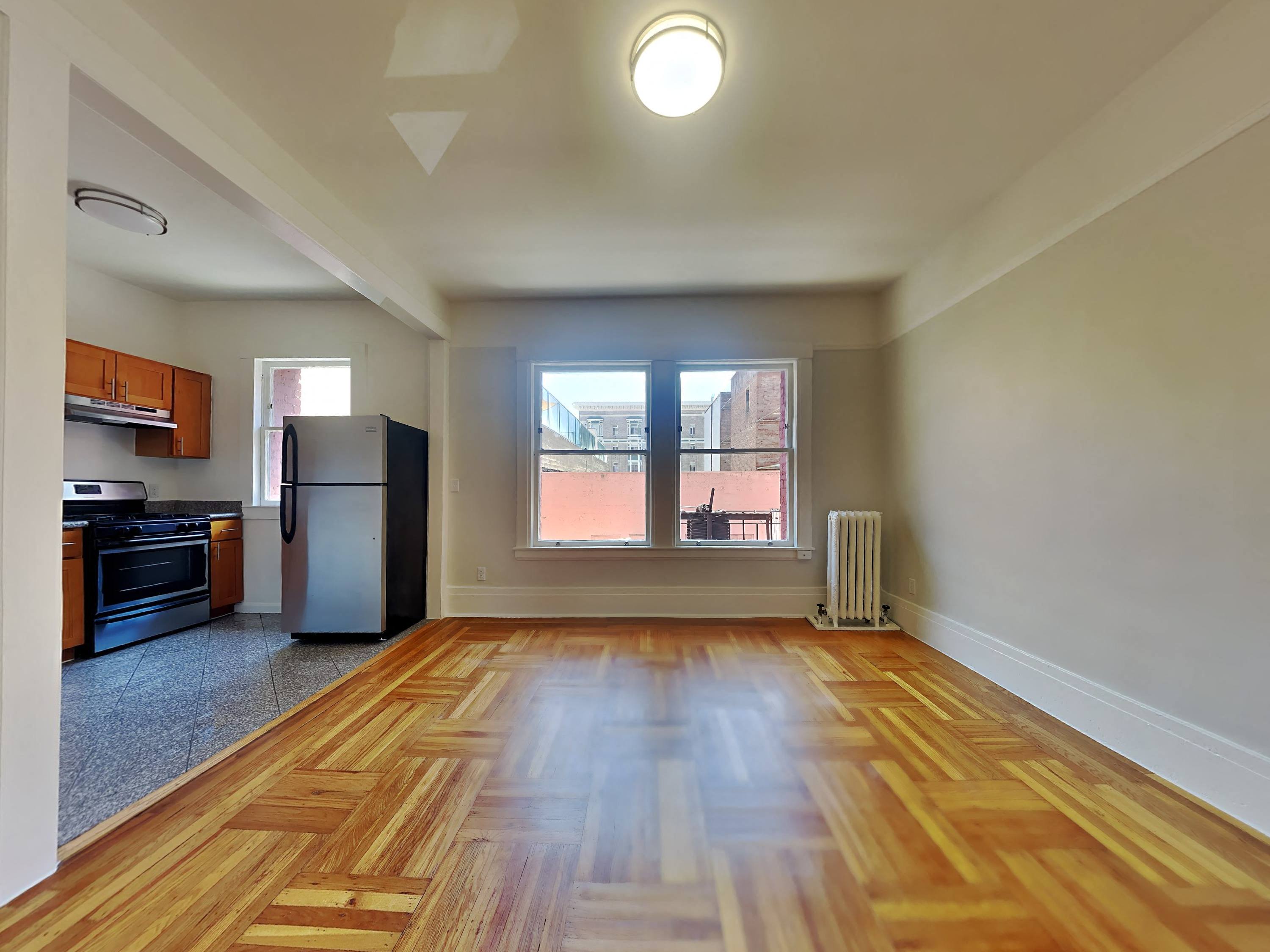 an empty living room with a large window and a kitchen