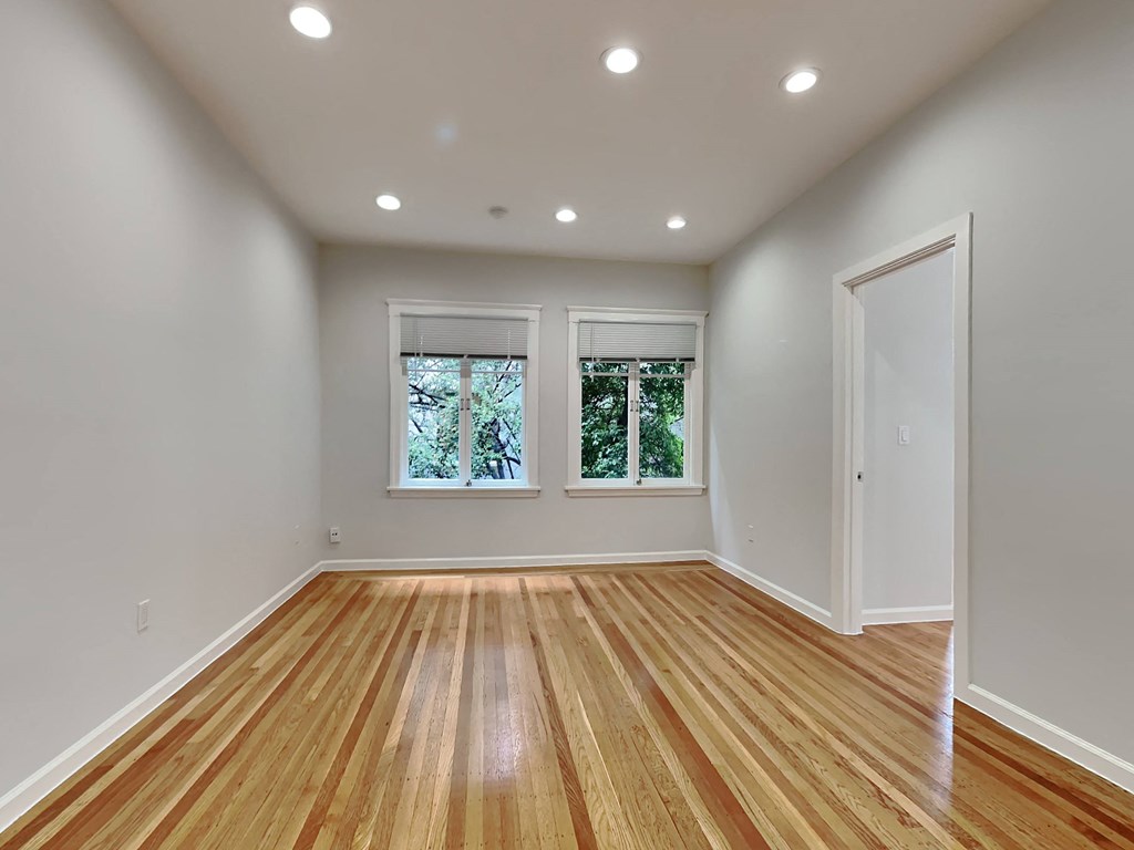 an empty living room with two windows and wood floors