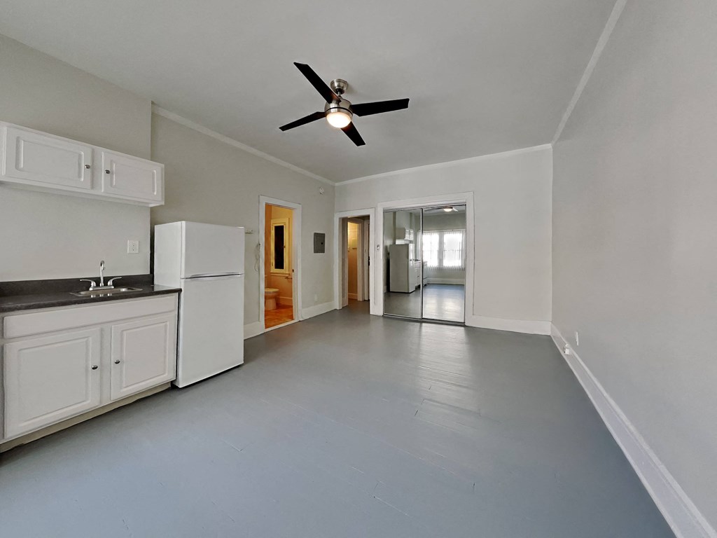 an empty kitchen with white cabinets and a ceiling fan