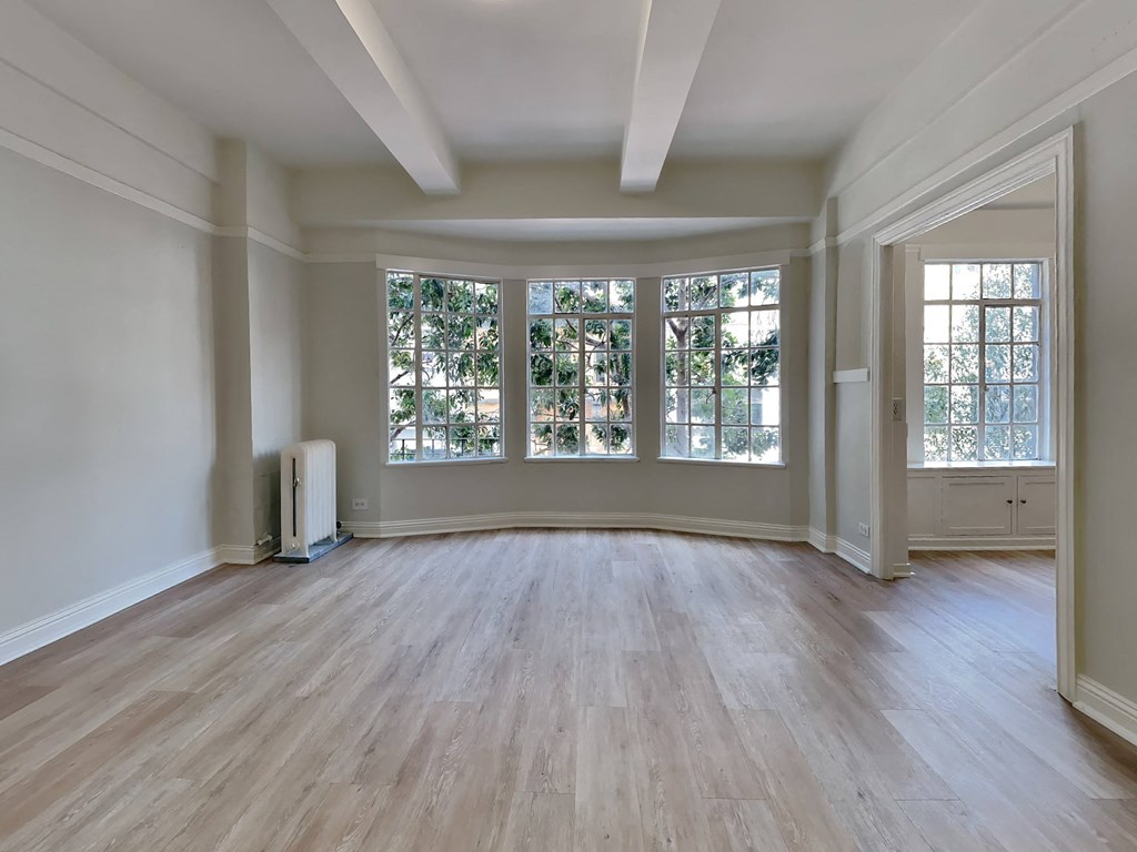 an empty living room with large windows and wood floors