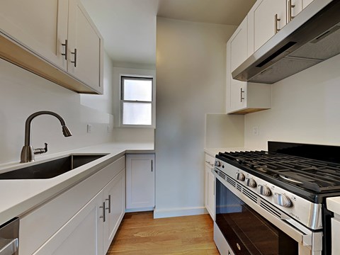 a kitchen with white cabinets and a stove and sink
