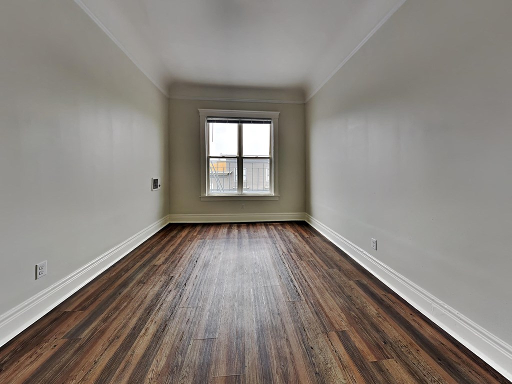 an empty room with wood floors and a window