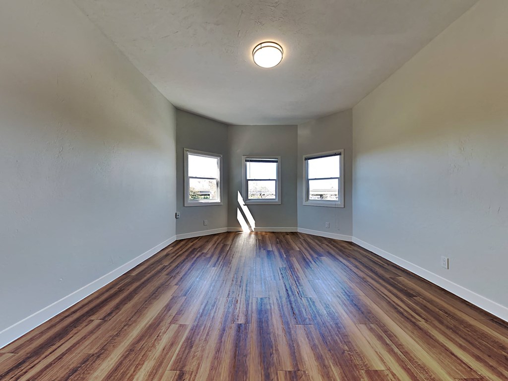 an empty living room with wood flooring and windows