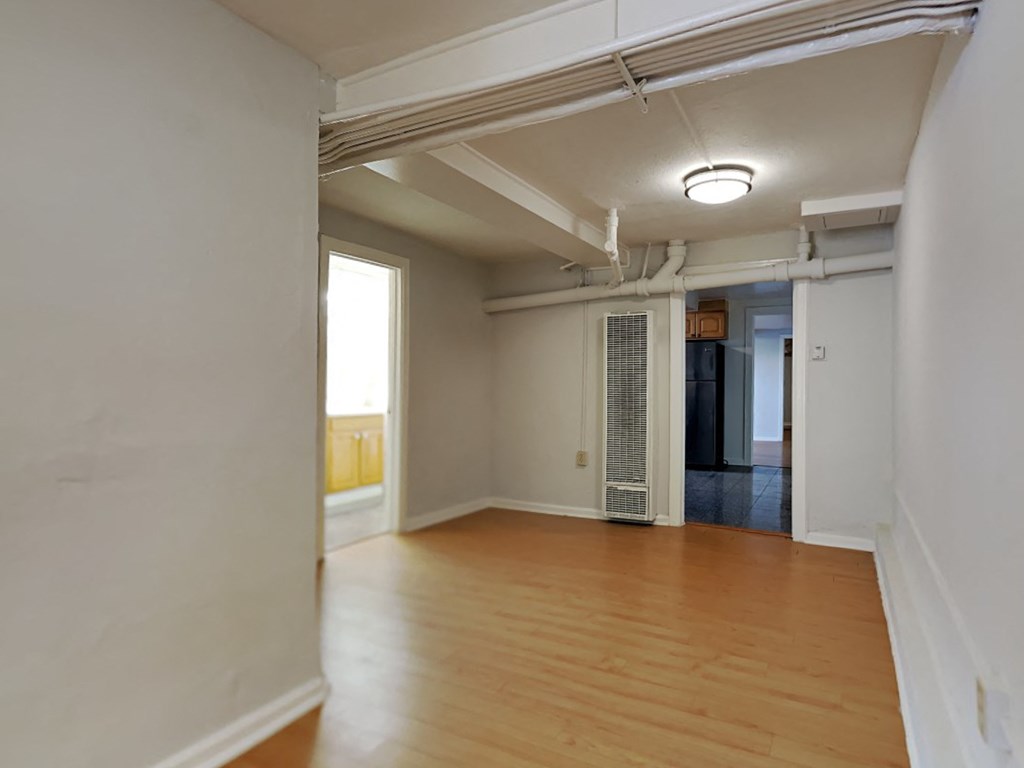 an empty living room with wood floors and white walls