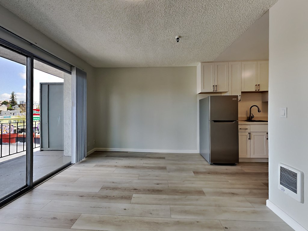the living room and kitchen of an apartment with a sliding glass door