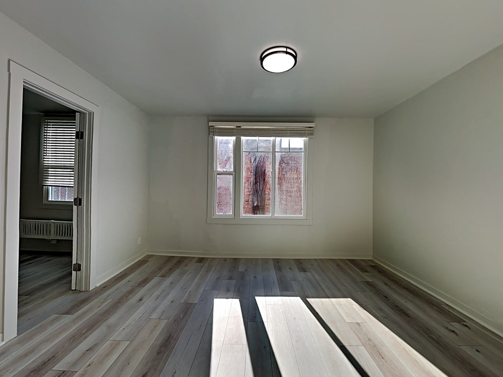 an empty room with wood floors and a window