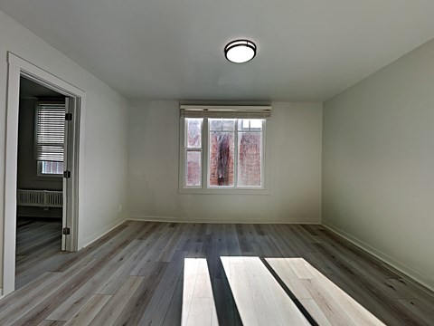 an empty room with wood floors and a window