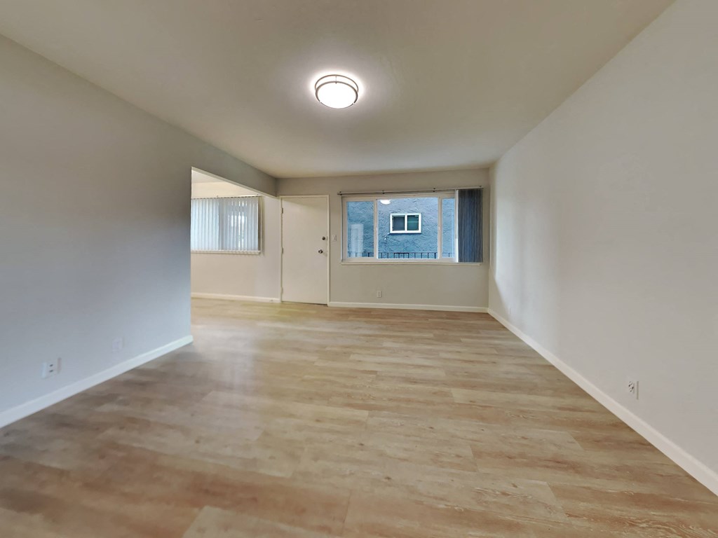 an empty living room with wood floors and a window