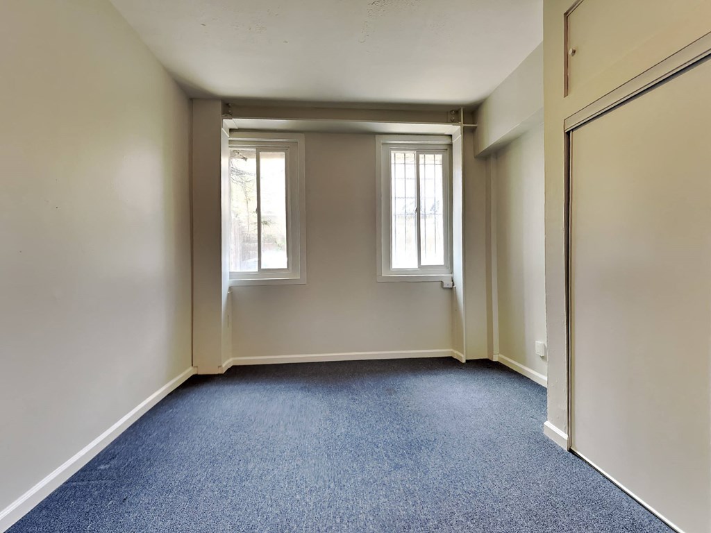 a empty room with two windows and blue carpet