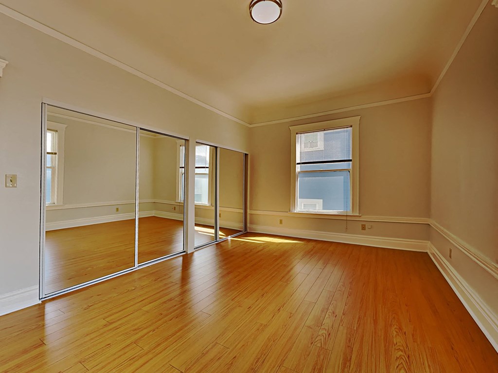 an empty living room with wood floors and mirrors