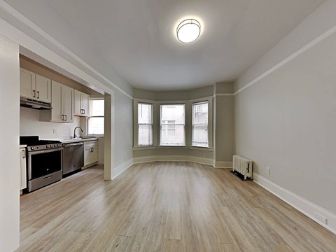 an empty living room and kitchen with wood floors and windows