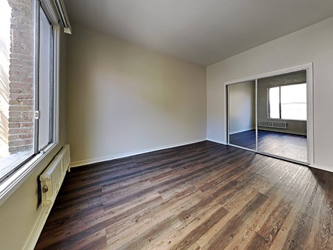an empty living room with wood flooring and a large window