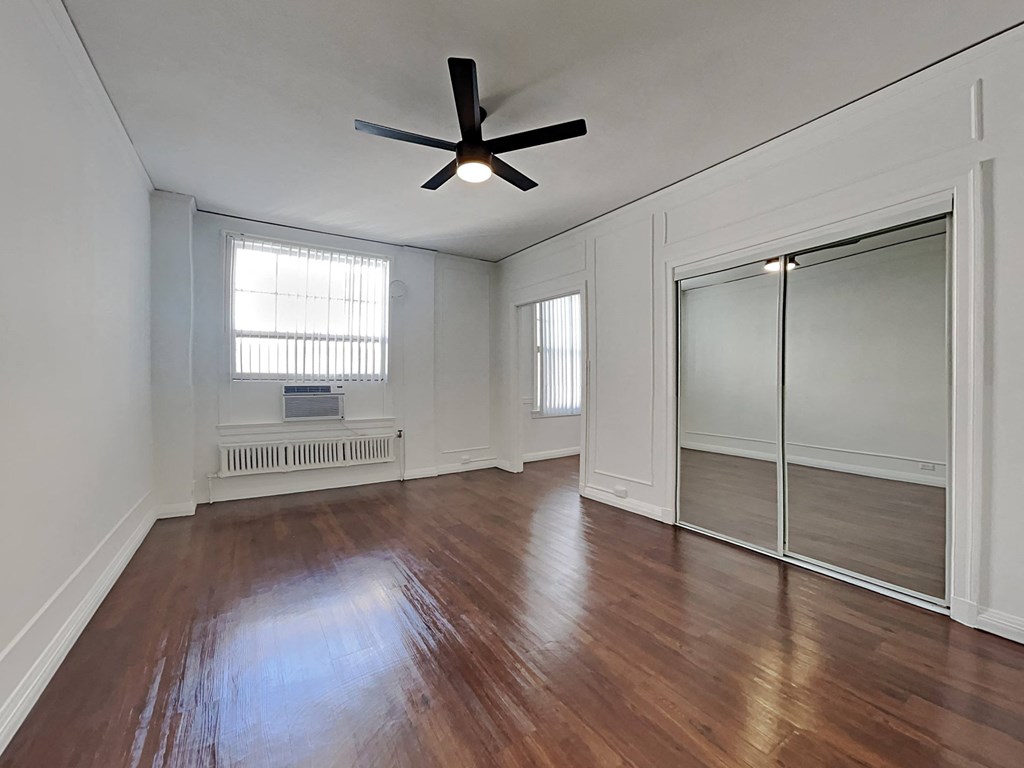 an empty living room with wood floors and a ceiling fan