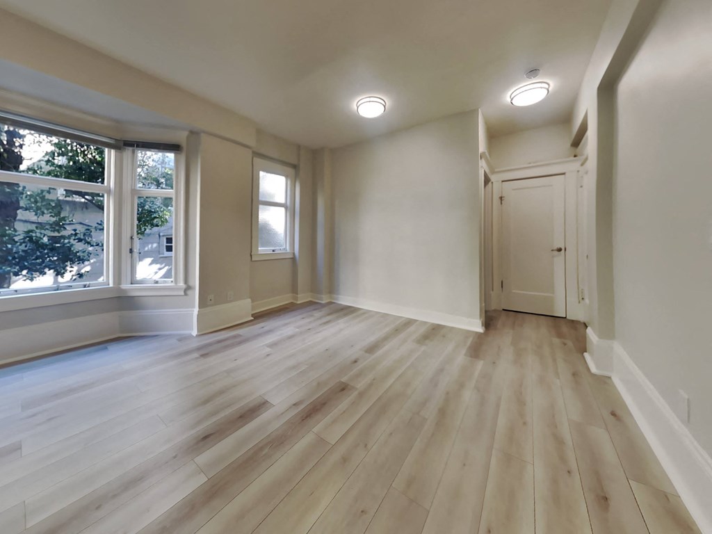 an empty living room with hardwood floors and a large window