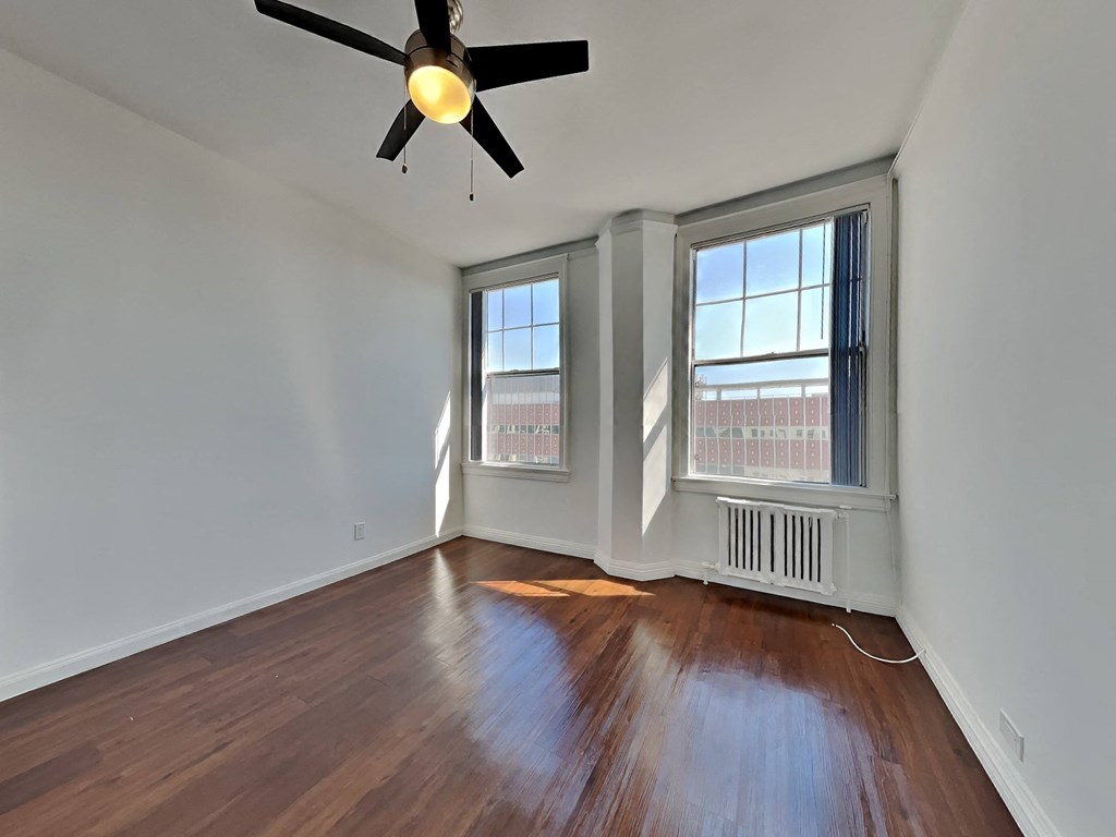 an empty living room with wood floors and a ceiling fan