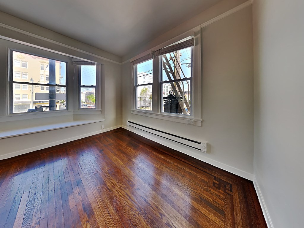 an empty living room with wood floors and three windows