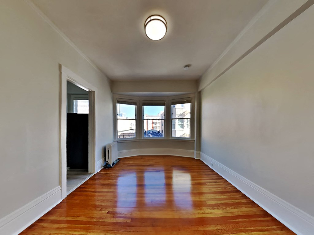 an empty living room with wood floors and a bay window