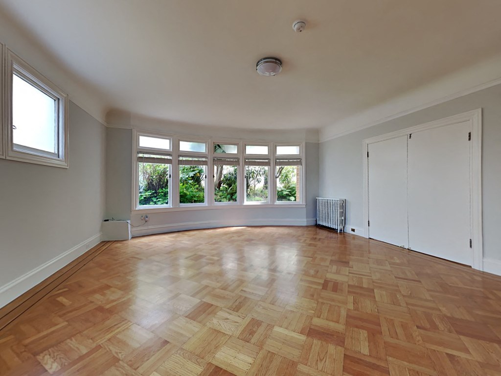 an empty living room with a large window and wooden floors
