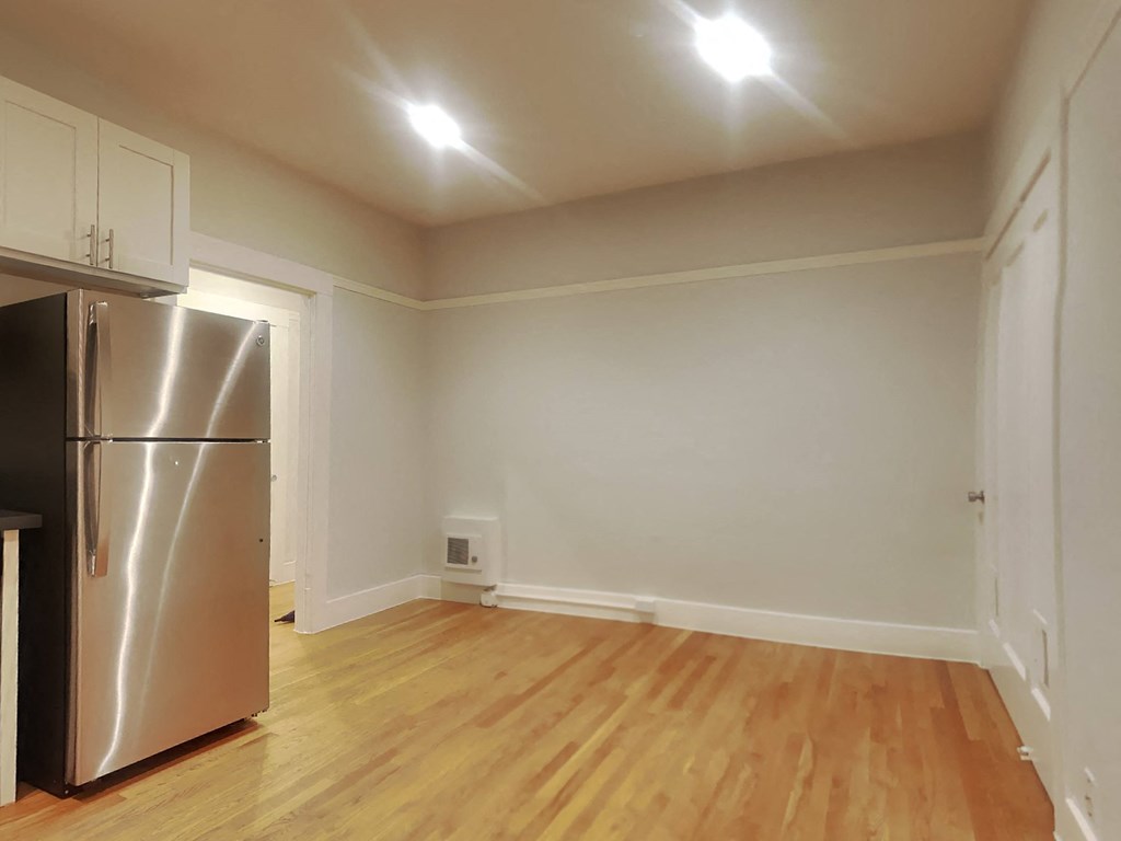 a kitchen with a stainless steel refrigerator and a wooden floor
