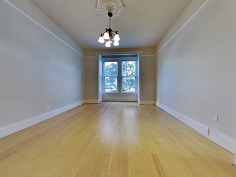 an empty living room with wood floors and a window