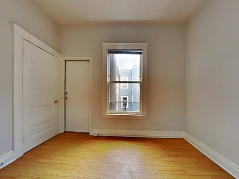a bedroom with a window and a door and a wooden floor