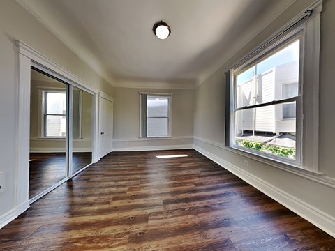 an empty living room with wood floors and a large window
