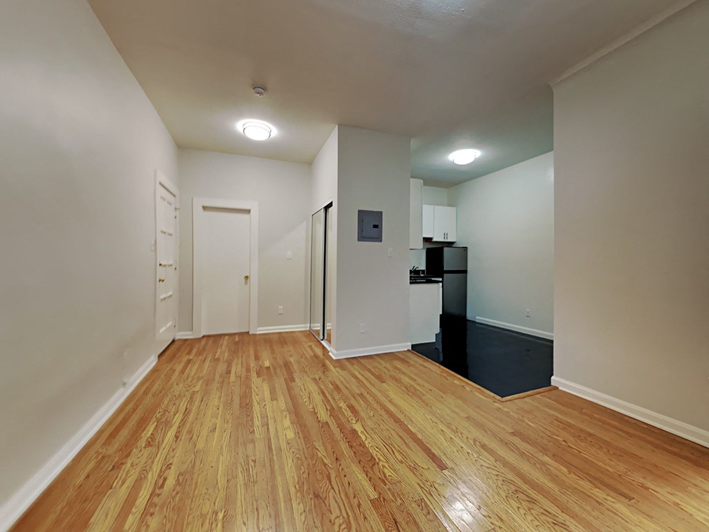 a renovated living room and kitchen with wood floors and white walls