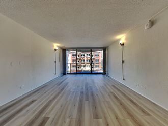 an empty living room with wood flooring and a balcony