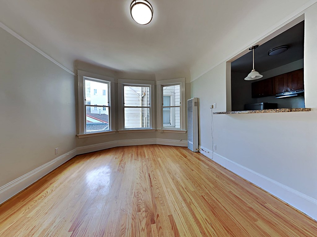 an empty living room with wood floors and a window