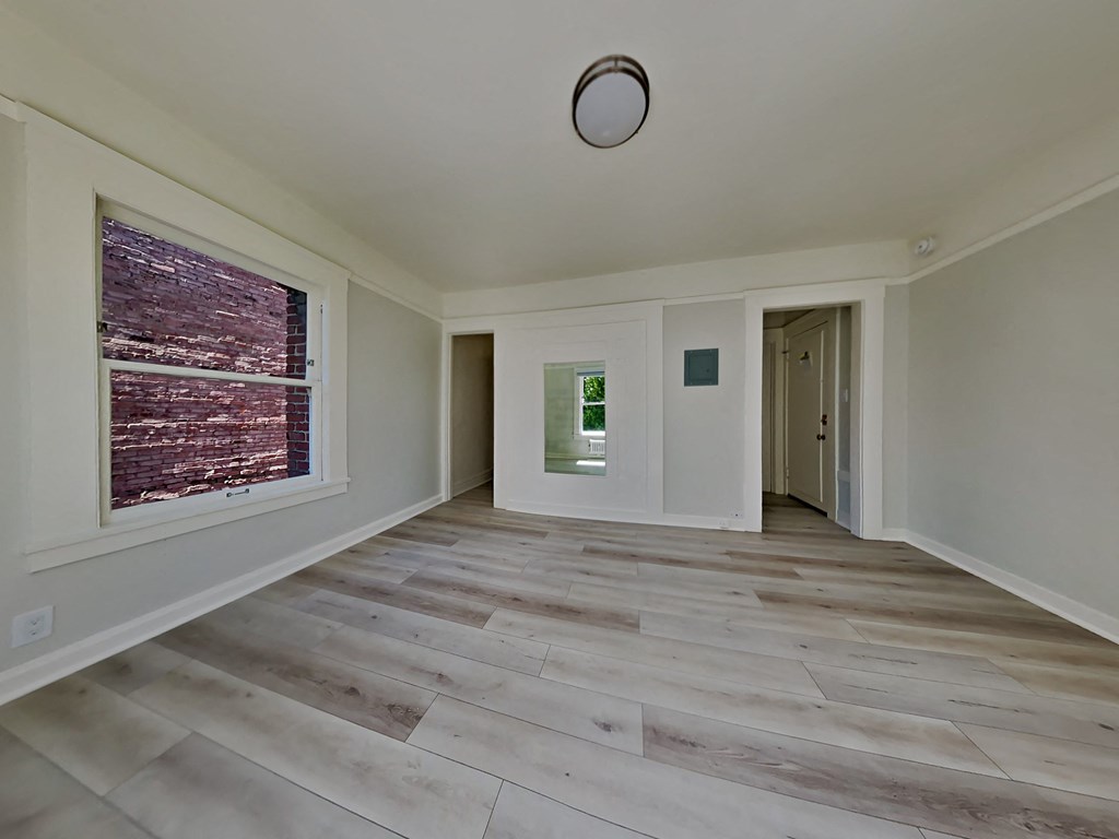 an empty living room with a large window and wooden floors