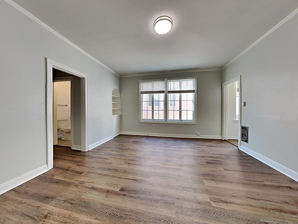 an empty living room with a window and a door to a bathroom