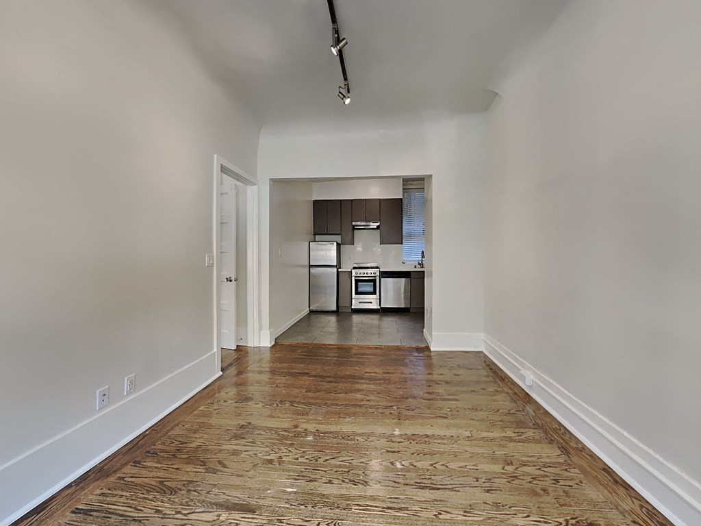 a living room and kitchen with wood floors and white walls