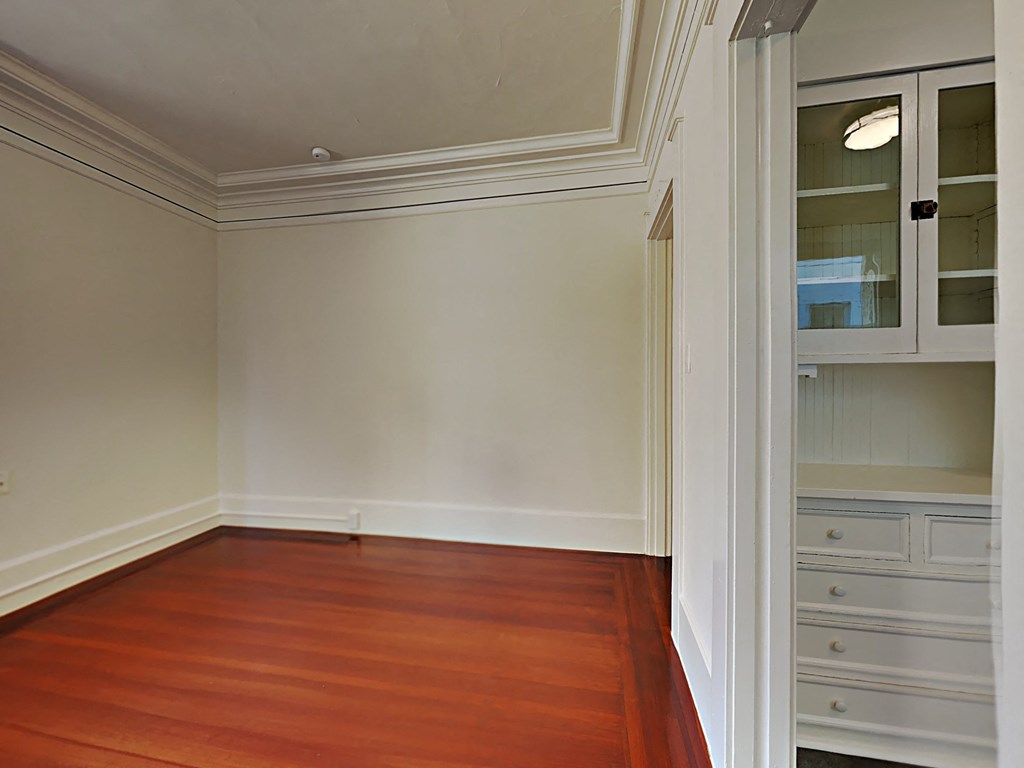a dining room with a wood floor and white cabinets