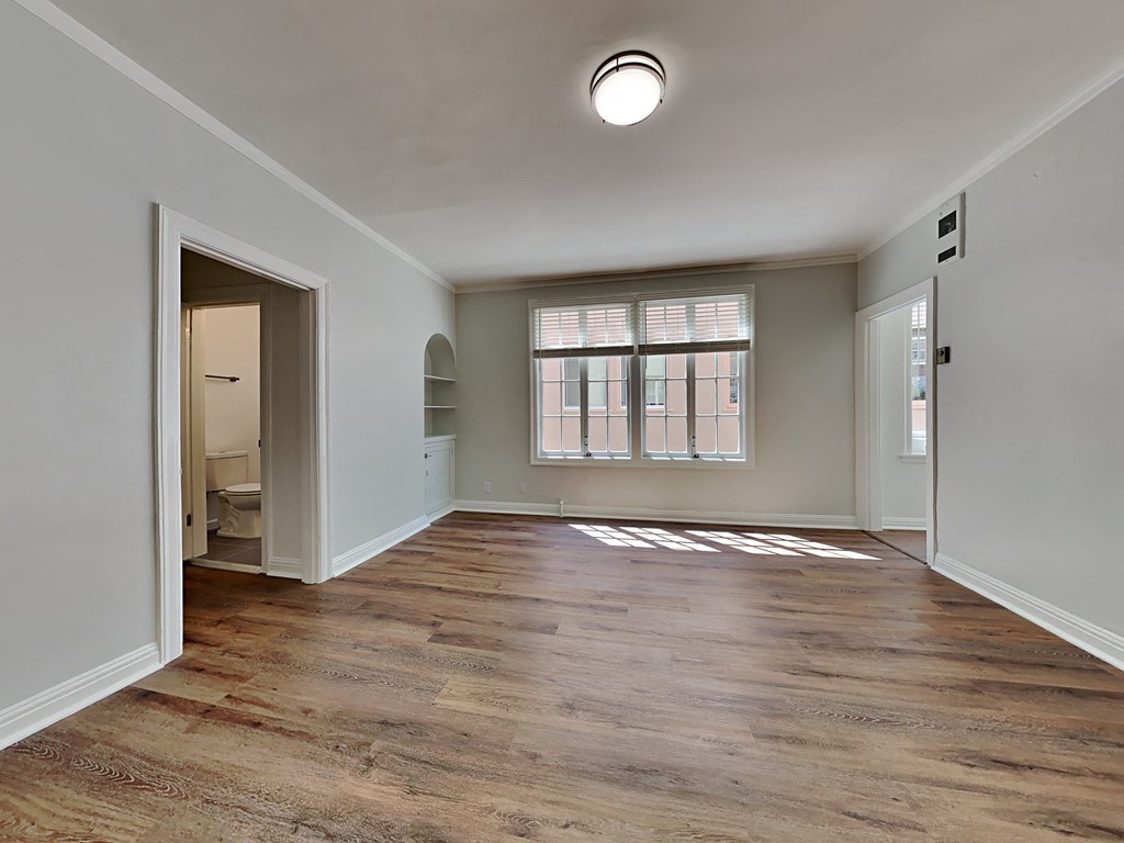 an empty living room with a large window and a door to a bathroom