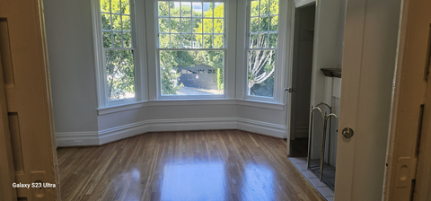 a living room with a large window and wooden floors