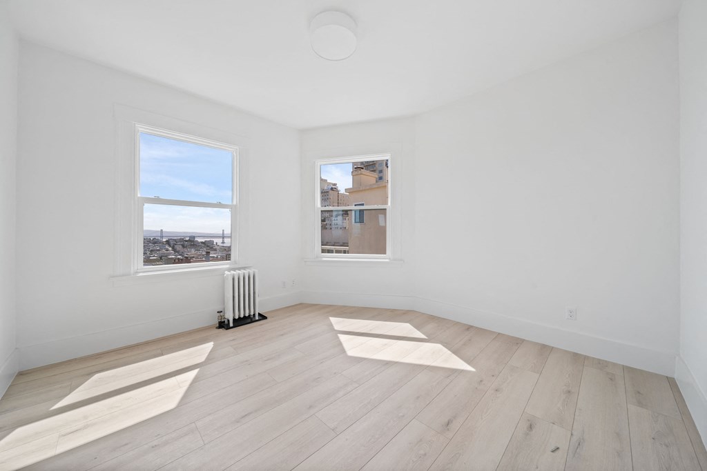 a living room with hardwood floors and two windows