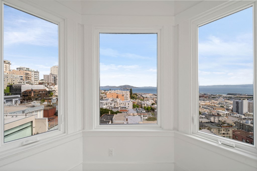 three windows in a room with a view of the city