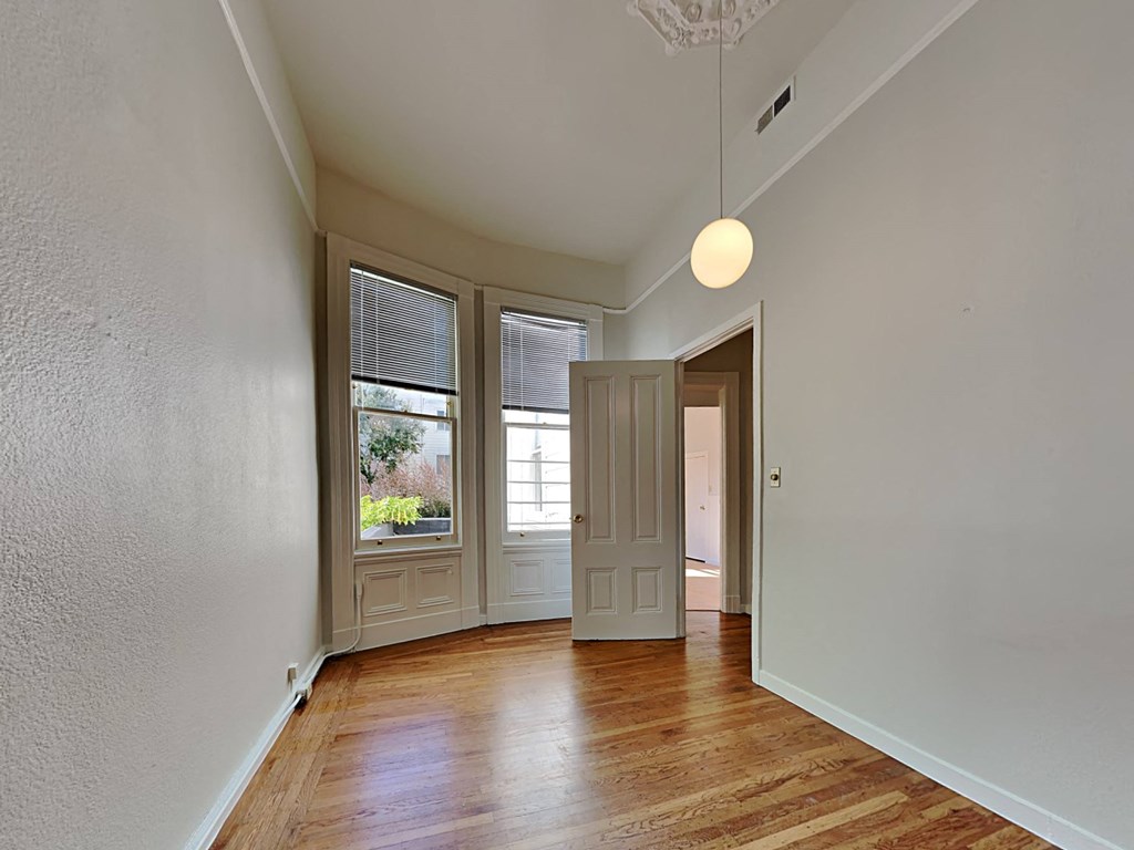 an empty living room with a door to a hallway and a window