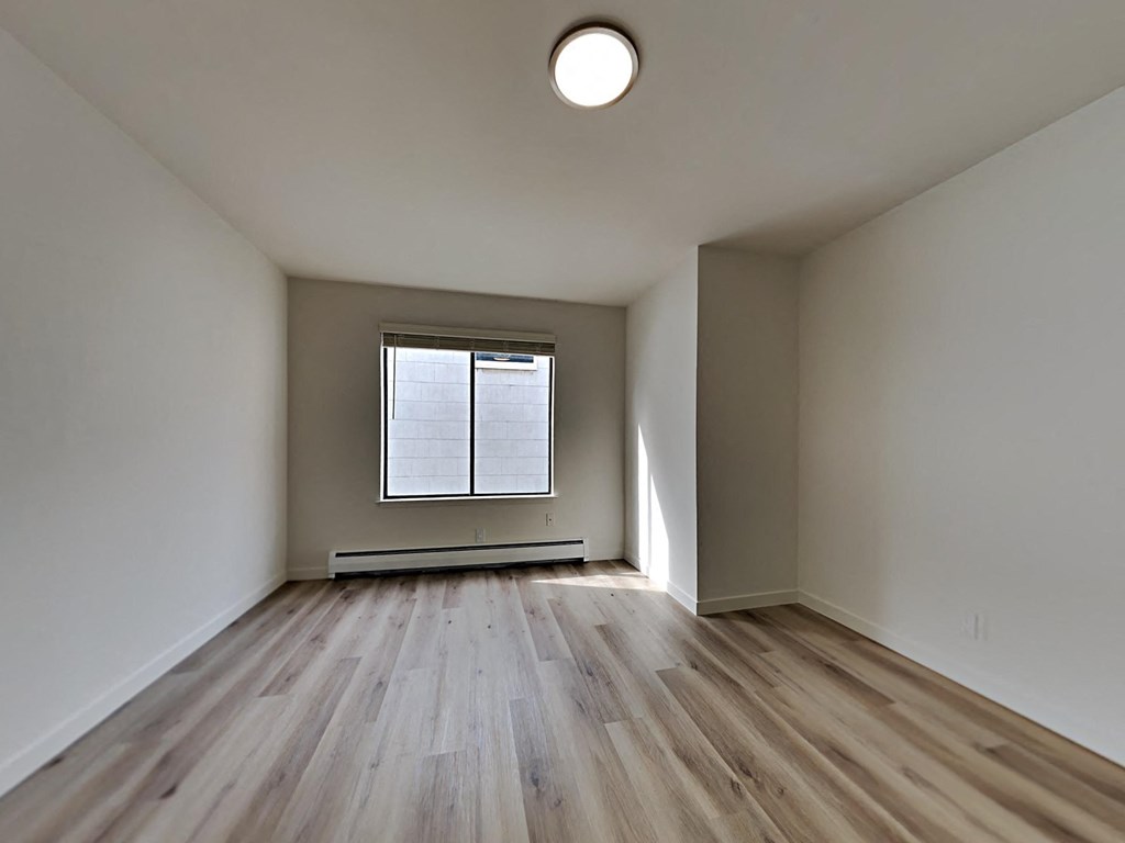 an empty living room with wood floors and a window