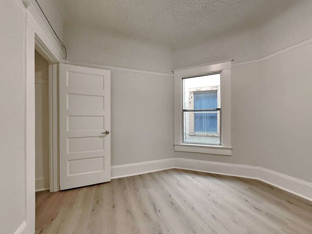 an empty bedroom with a window and a white door