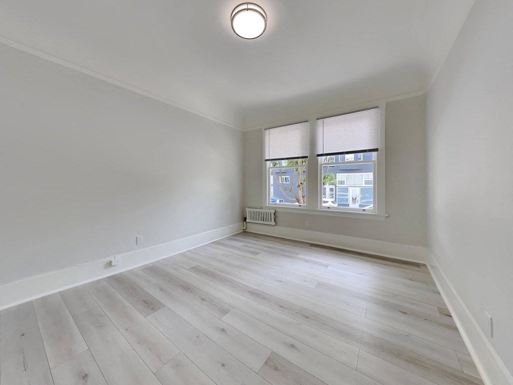 an empty living room with wood floors and a window