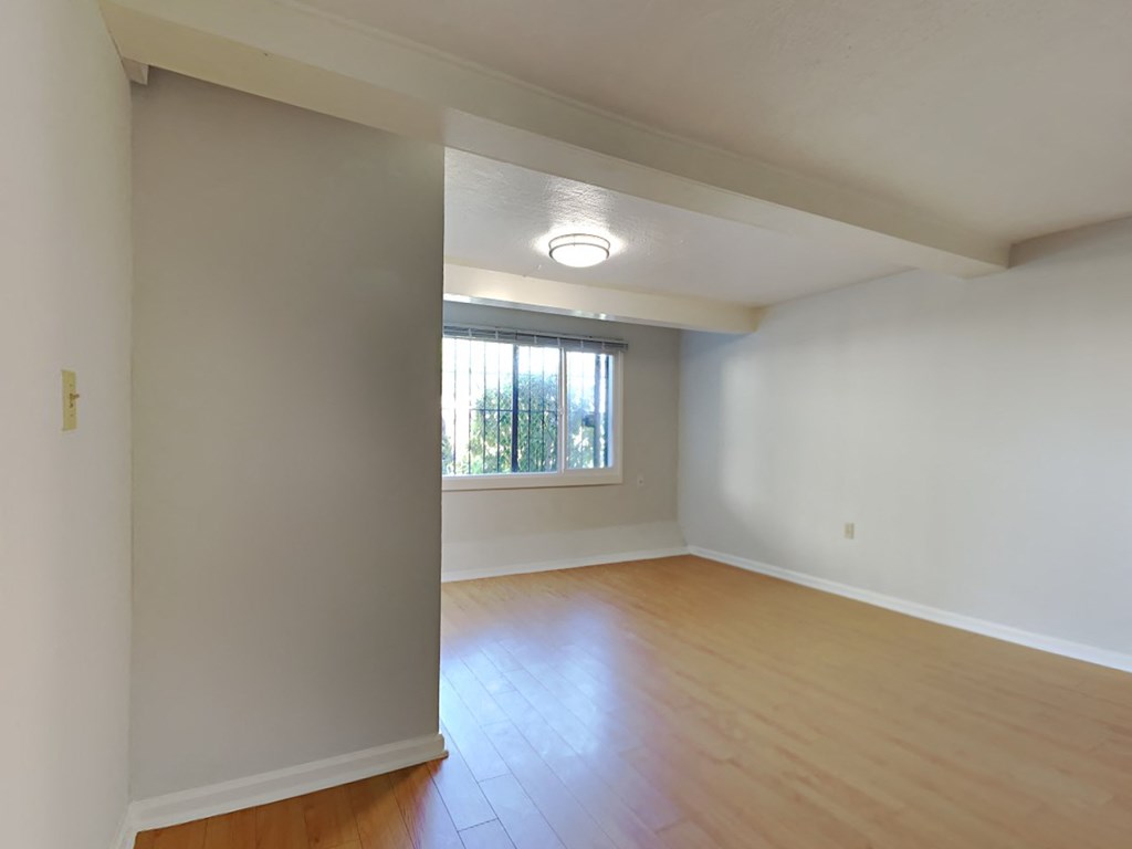 an empty living room with wood floors and a window